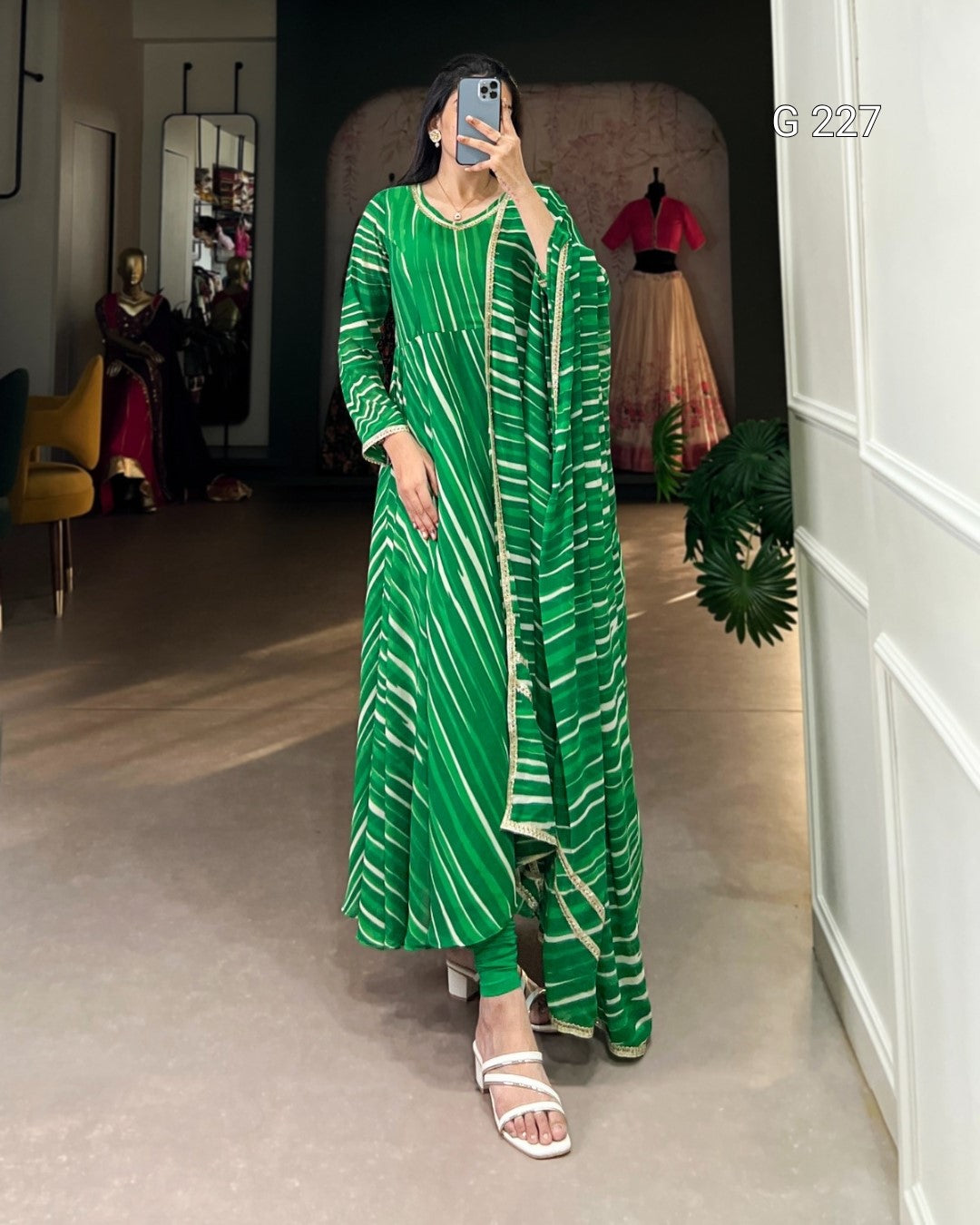 Person wearing a green and white patterned outfit in a room with mirrors and furniture.