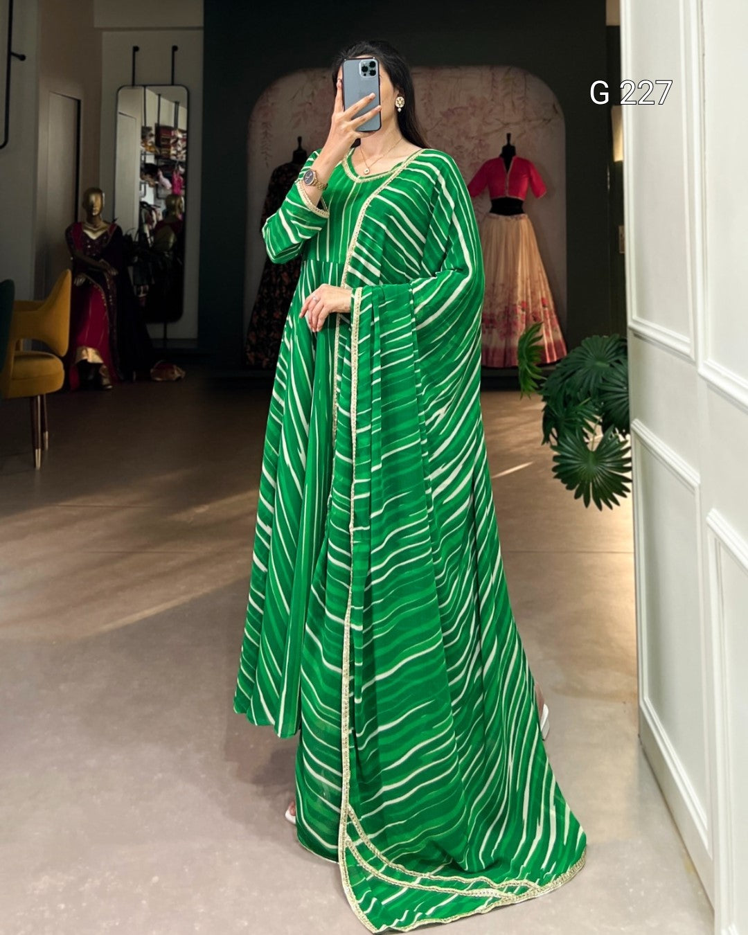 Person wearing a green and white striped dress taking a mirror selfie.