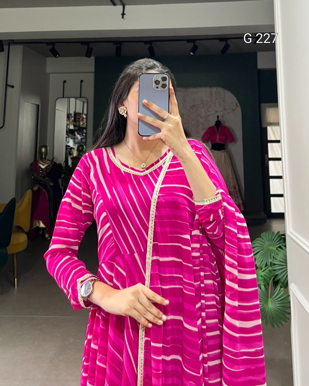 Woman taking a mirror selfie wearing a pink and white striped dress in a store setting.