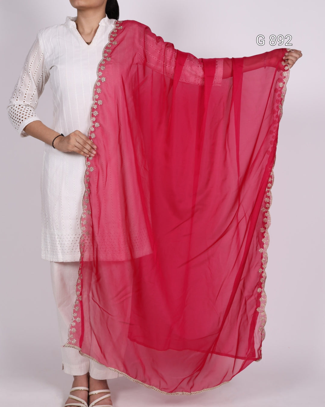 Person wearing a white outfit with a red dupatta draped over one shoulder on a white background