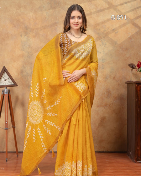 Woman wearing a yellow saree with white patterns against a brown background
