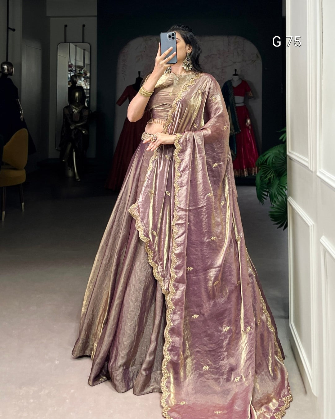Person wearing a traditional outfit with gold and pink details in an indoor setting.