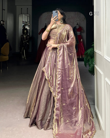 Person wearing a traditional outfit with gold and pink details in an indoor setting.