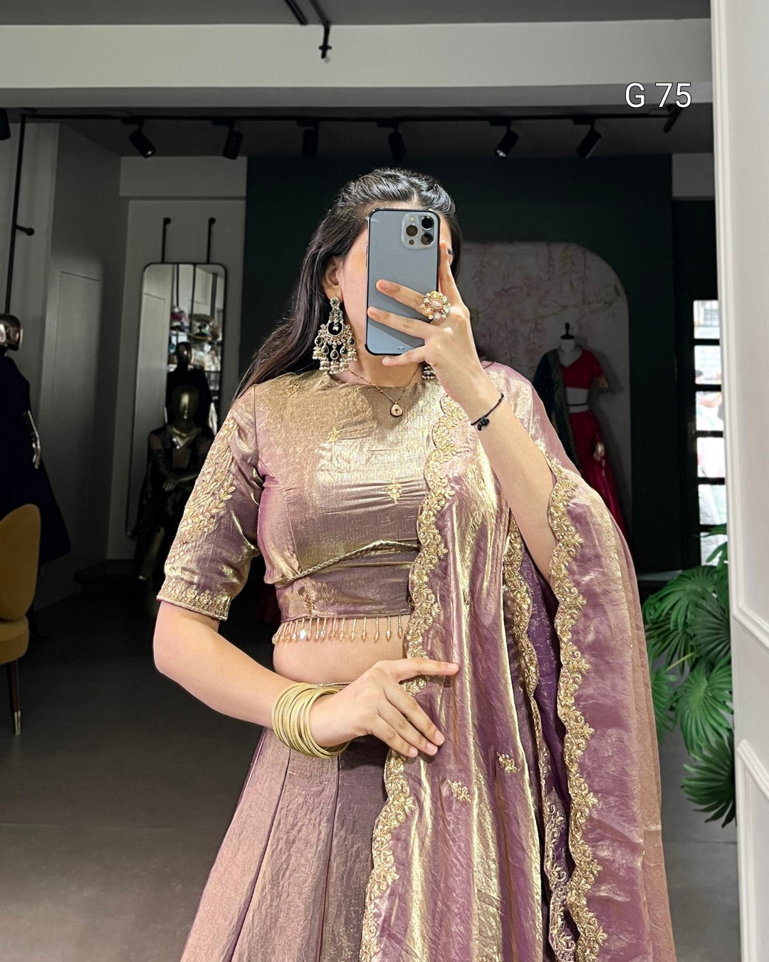 Person wearing a traditional outfit with a purple and gold color scheme, taking a mirror selfie.