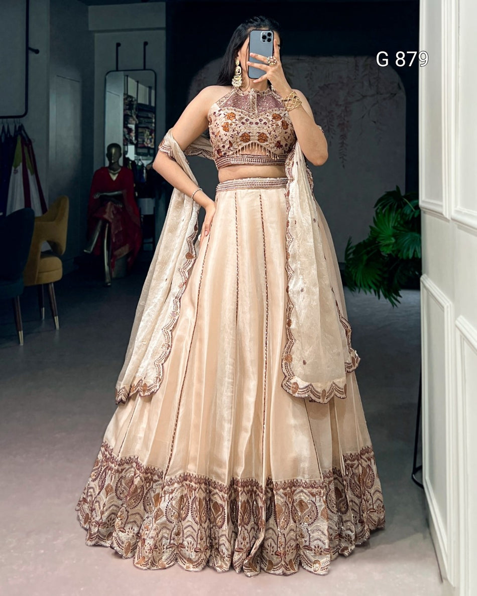 Beige and brown embroidered traditional outfit worn by a person indoors.