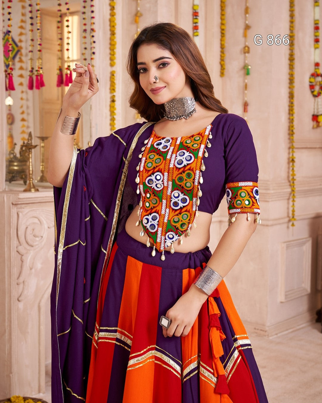 Woman wearing a traditional outfit with a colorful top and red skirt in a decorated room.