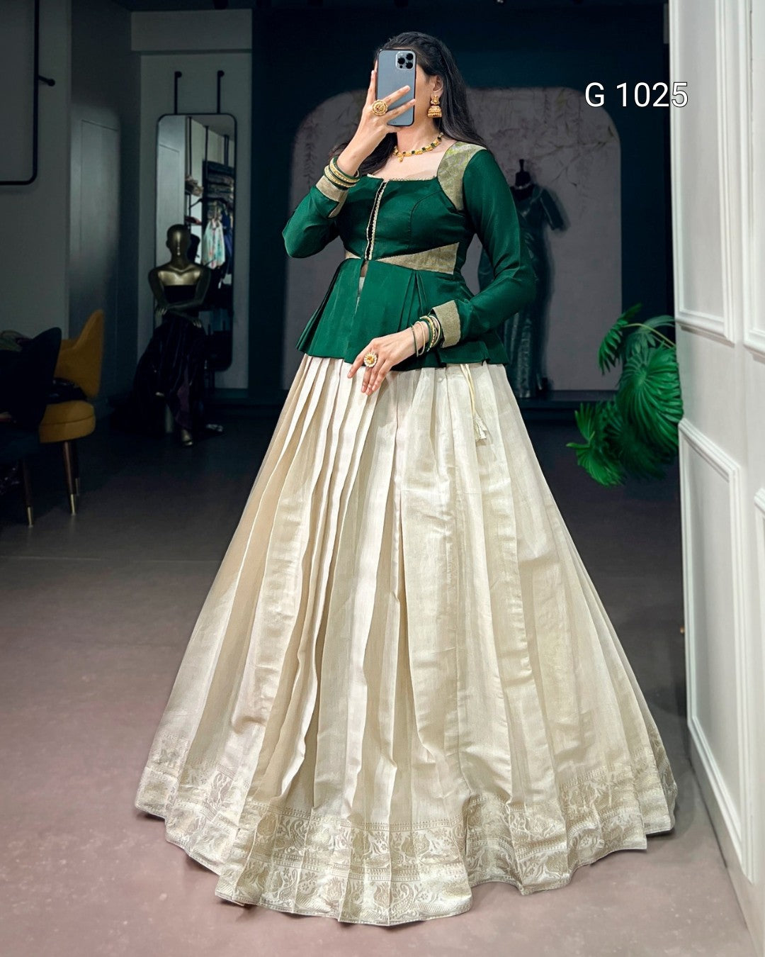 A woman takes a mirror selfie wearing a traditional Indian ethnic gown with a dark green embroidered bodice and a voluminous cream-colored flared skirt. The text 'G 1025' is visible in the top right corner.