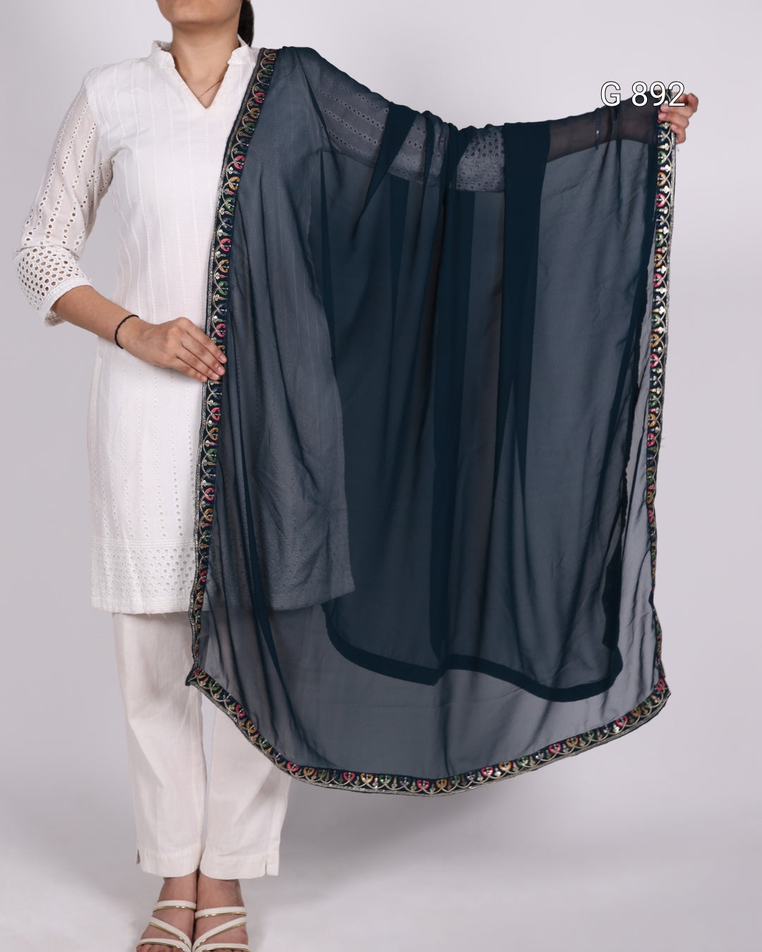 Person holding a dark blue dupatta with a colorful border on a white background