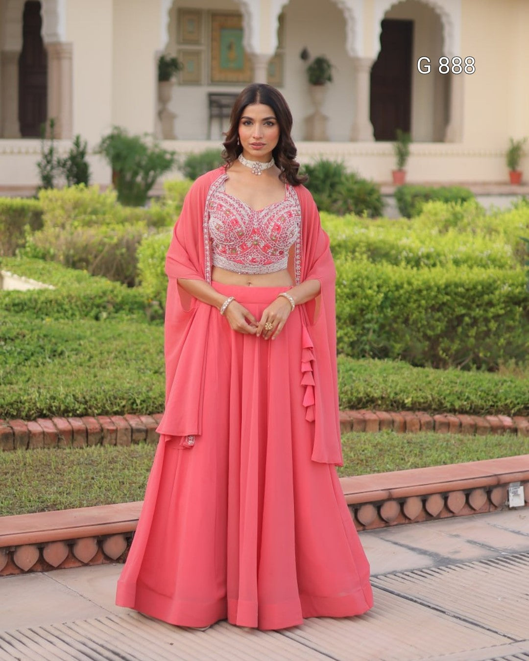 Woman in a pink traditional outfit standing in a garden setting