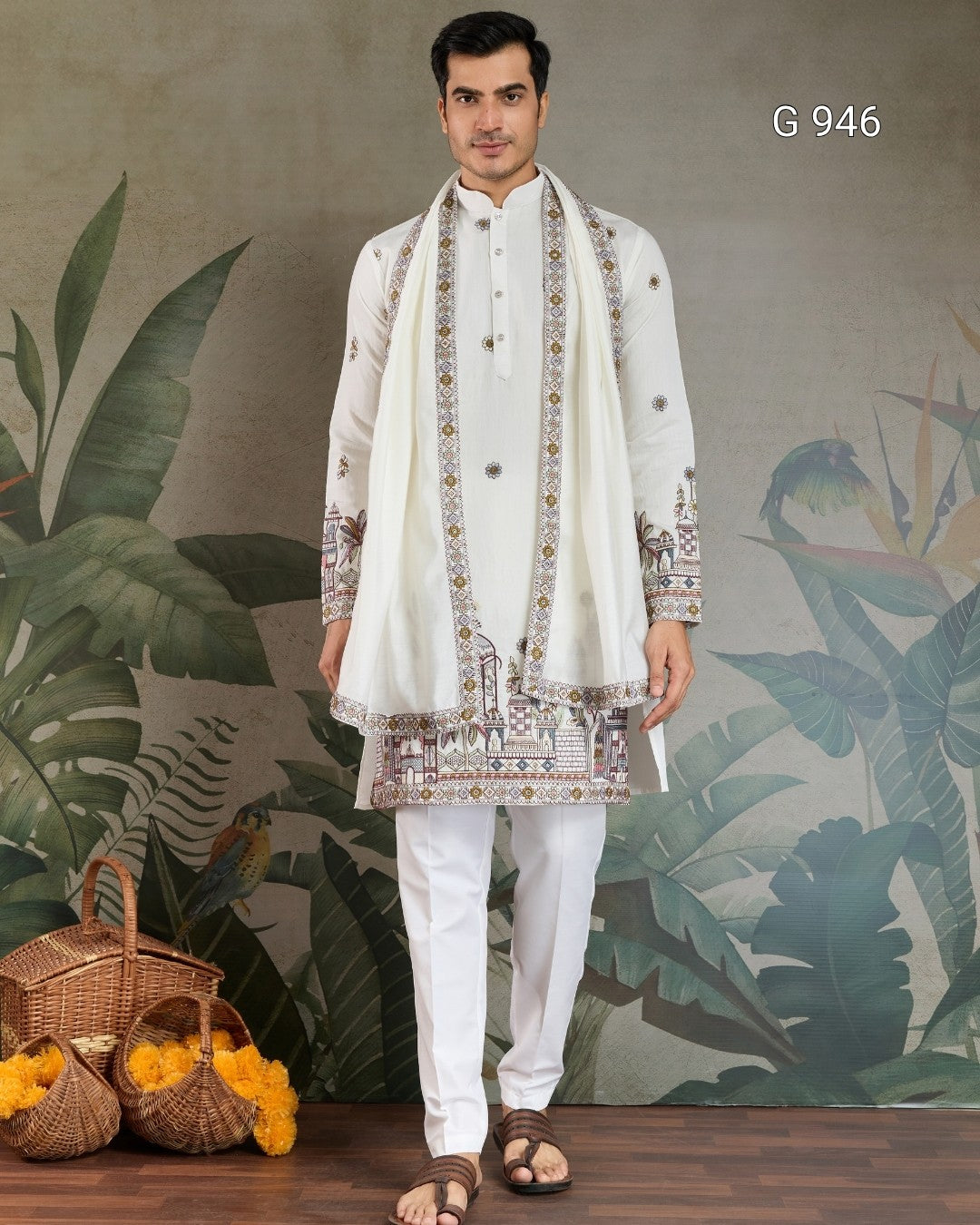 Man wearing a traditional white kurta with embroidery against a decorative wall.