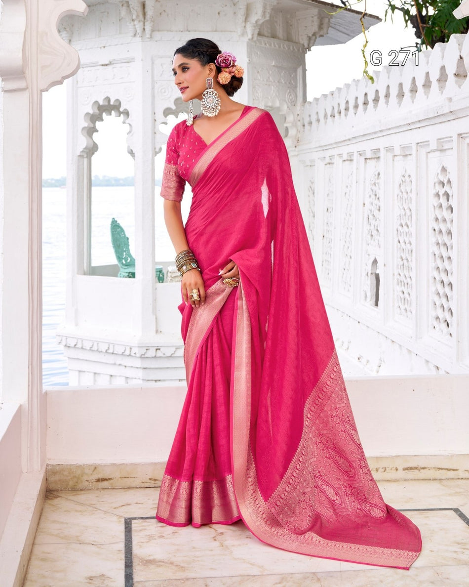 A woman models a bright pink saree with a matching pink blouse in an outdoor architectural setting with white walls and a marble floor.