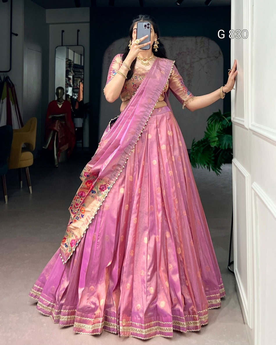 Woman in a pink saree with gold patterns taking a mirror selfie.