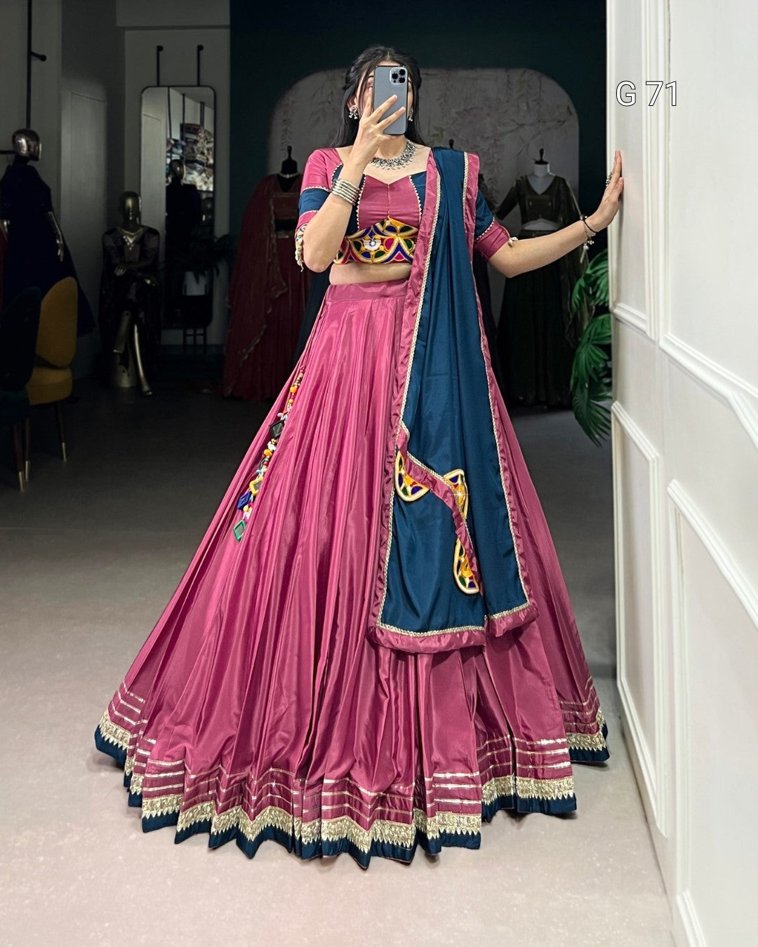 Person wearing a traditional pink and blue outfit with colorful patterns in a room.