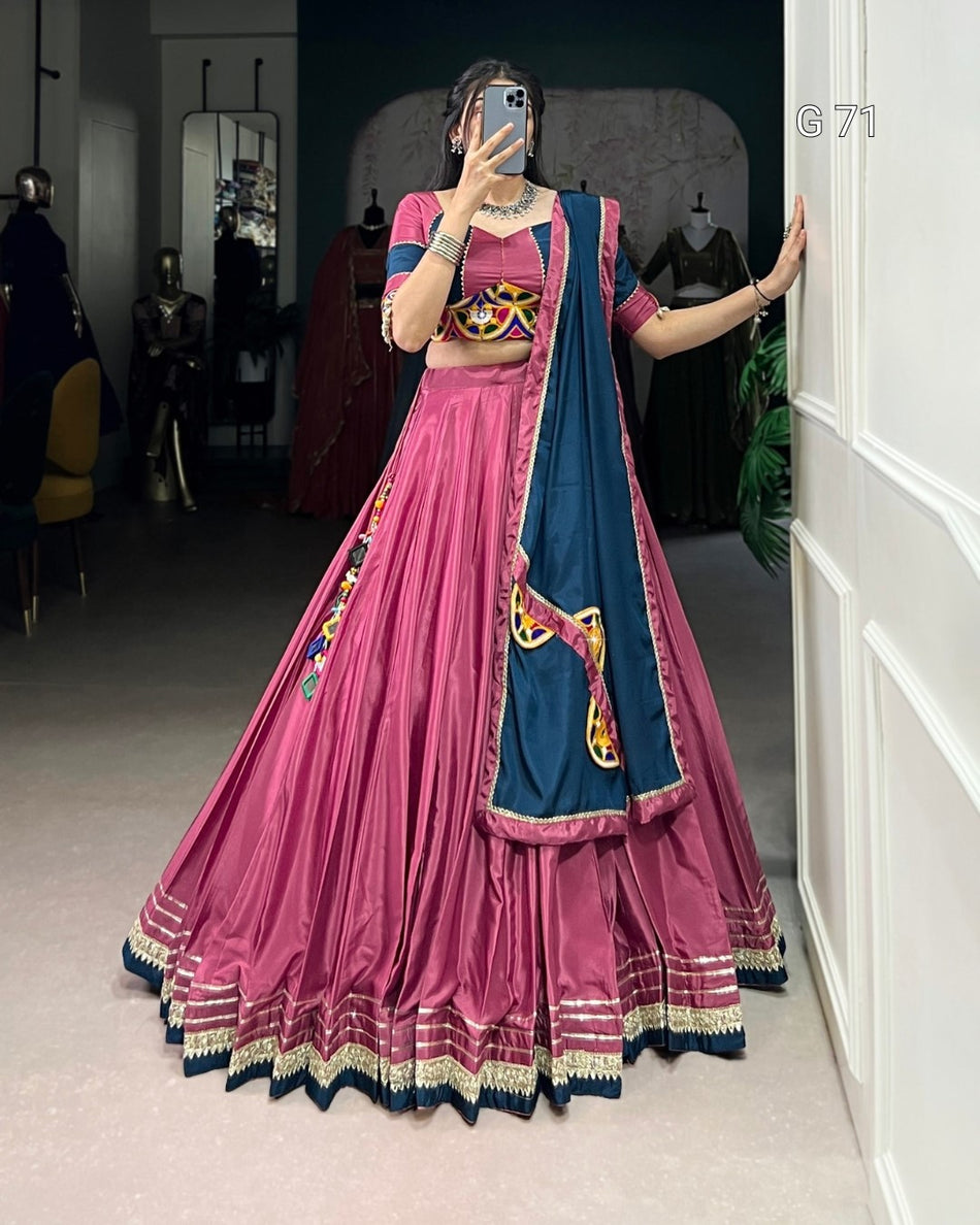 Person wearing a traditional pink and blue outfit with colorful patterns in a room.