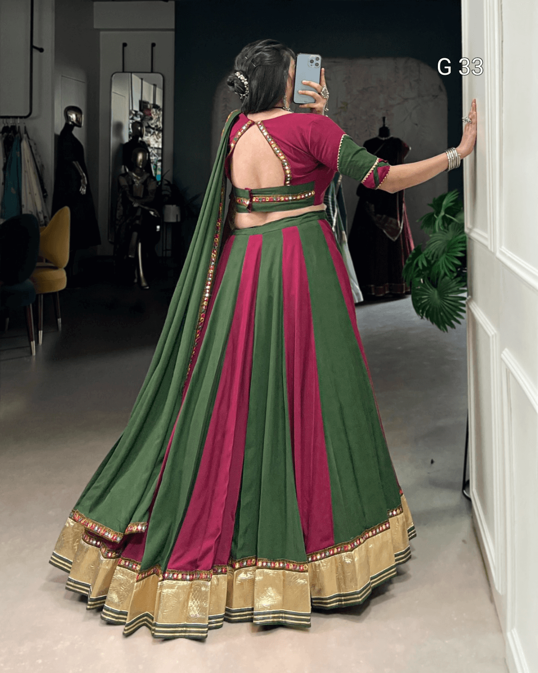 Woman in a green and pink traditional outfit taking a mirror selfie.