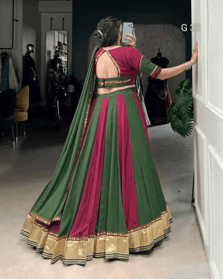 Woman in a green and pink traditional outfit taking a mirror selfie.