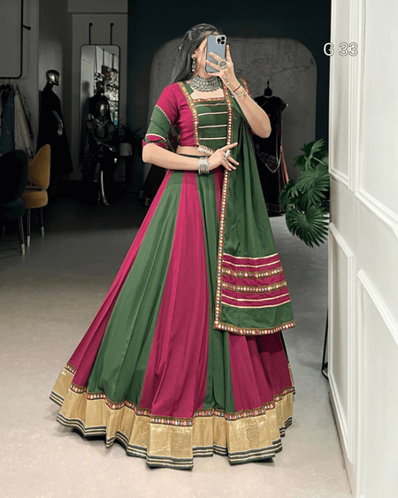 Woman wearing a green and pink traditional outfit in a room.