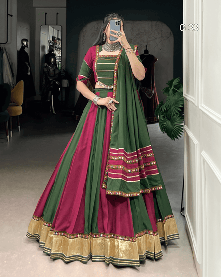 Person wearing a green and red traditional outfit with gold details, standing in a room.