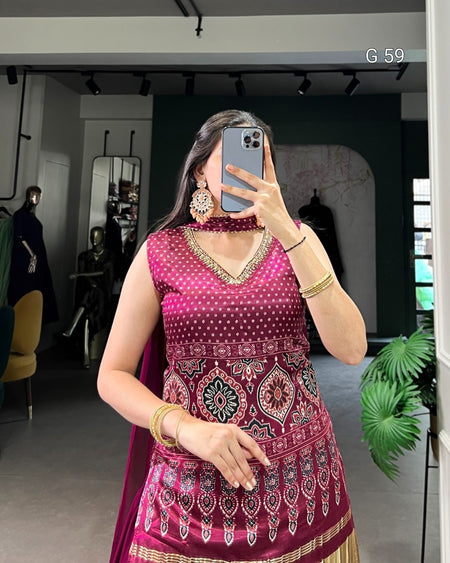 Woman taking a mirror selfie wearing a pink traditional outfit with intricate patterns.