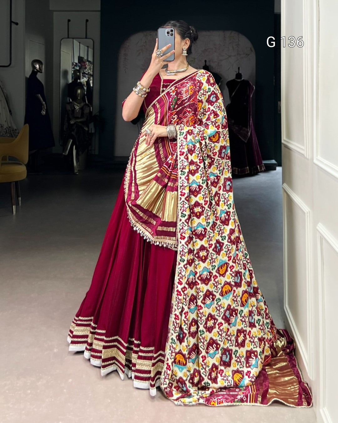 Person wearing a vibrant saree with a floral pattern in a room.