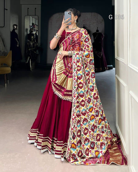 Person wearing a vibrant saree with a floral pattern in a room.