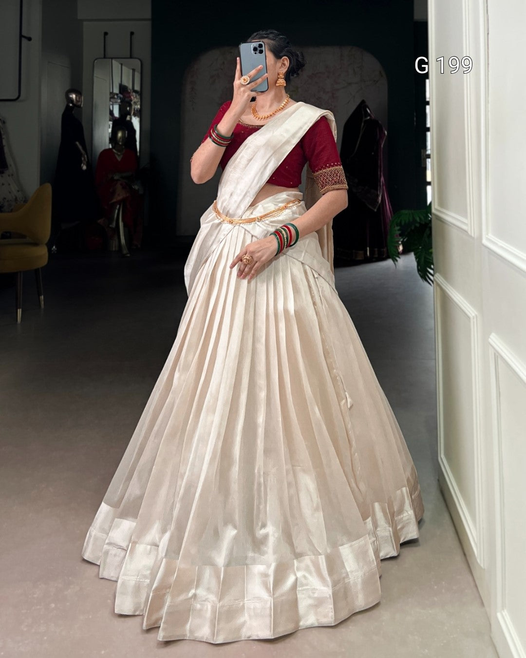 Woman wearing a white saree with a red blouse in a room.