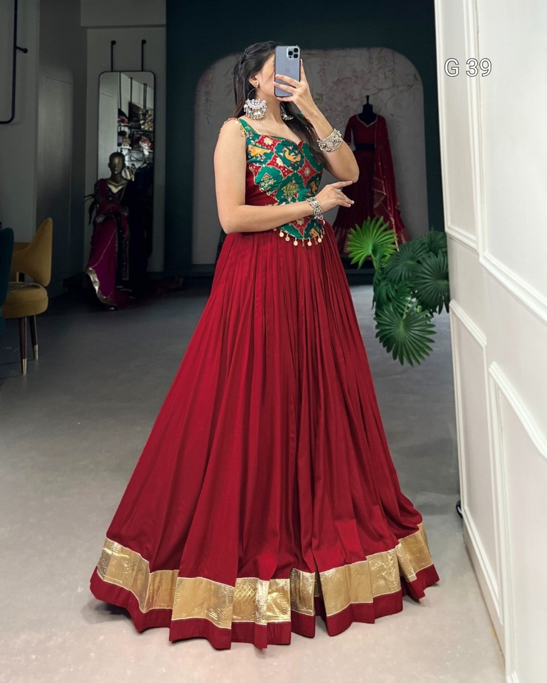 Woman in a red traditional outfit with gold details taking a mirror selfie.