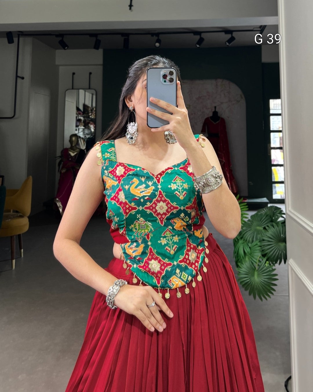 Person wearing a colorful traditional outfit with a red skirt, taking a mirror selfie.