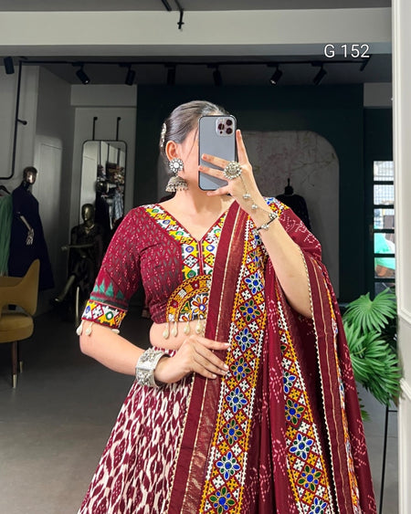 Person wearing a colorful saree with a patterned blouse in an indoor setting.