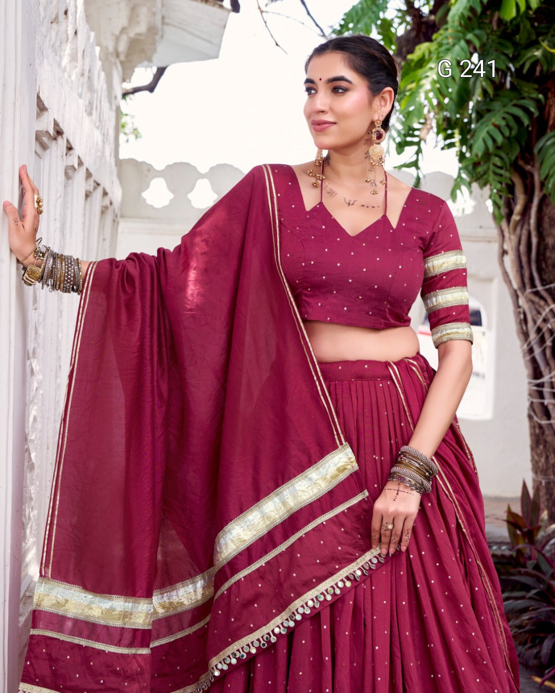 Woman wearing a maroon saree with gold trim in an outdoor setting