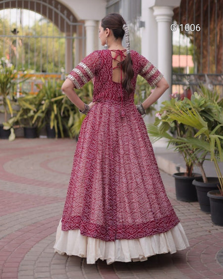 A woman wearing a traditional Indian salwar kameez dress, shown from the back in an outdoor courtyard setting. The dress features a deep magenta-pink printed kameez body with a cream-colored inner skirt and patterned sleeves.