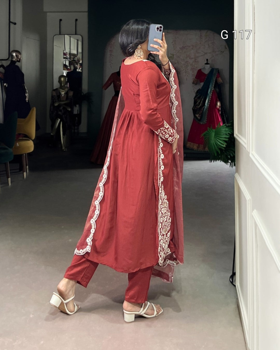 Person wearing a red traditional outfit with white embroidery in a room.