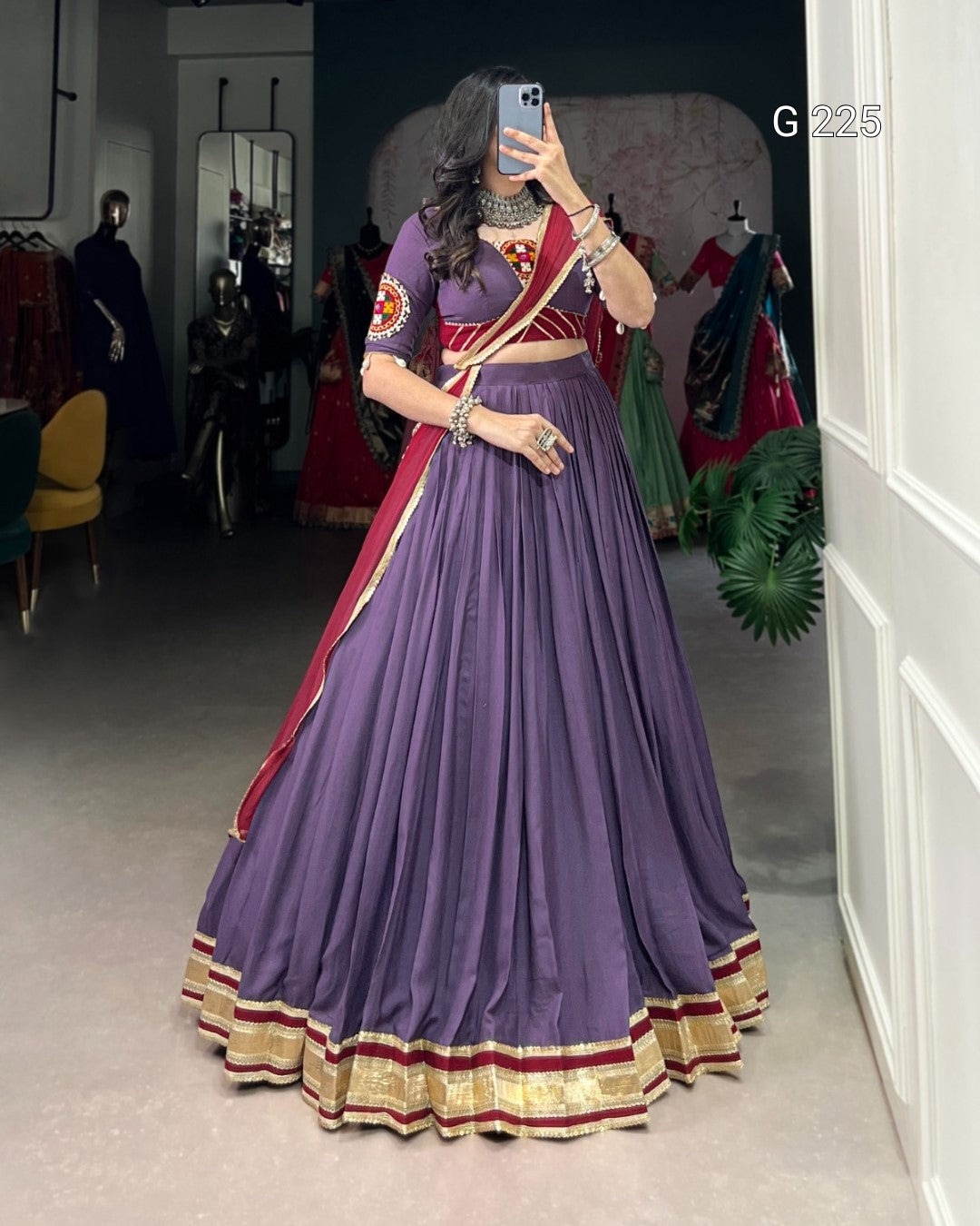 Person wearing a traditional purple outfit with red and gold accents in a room.