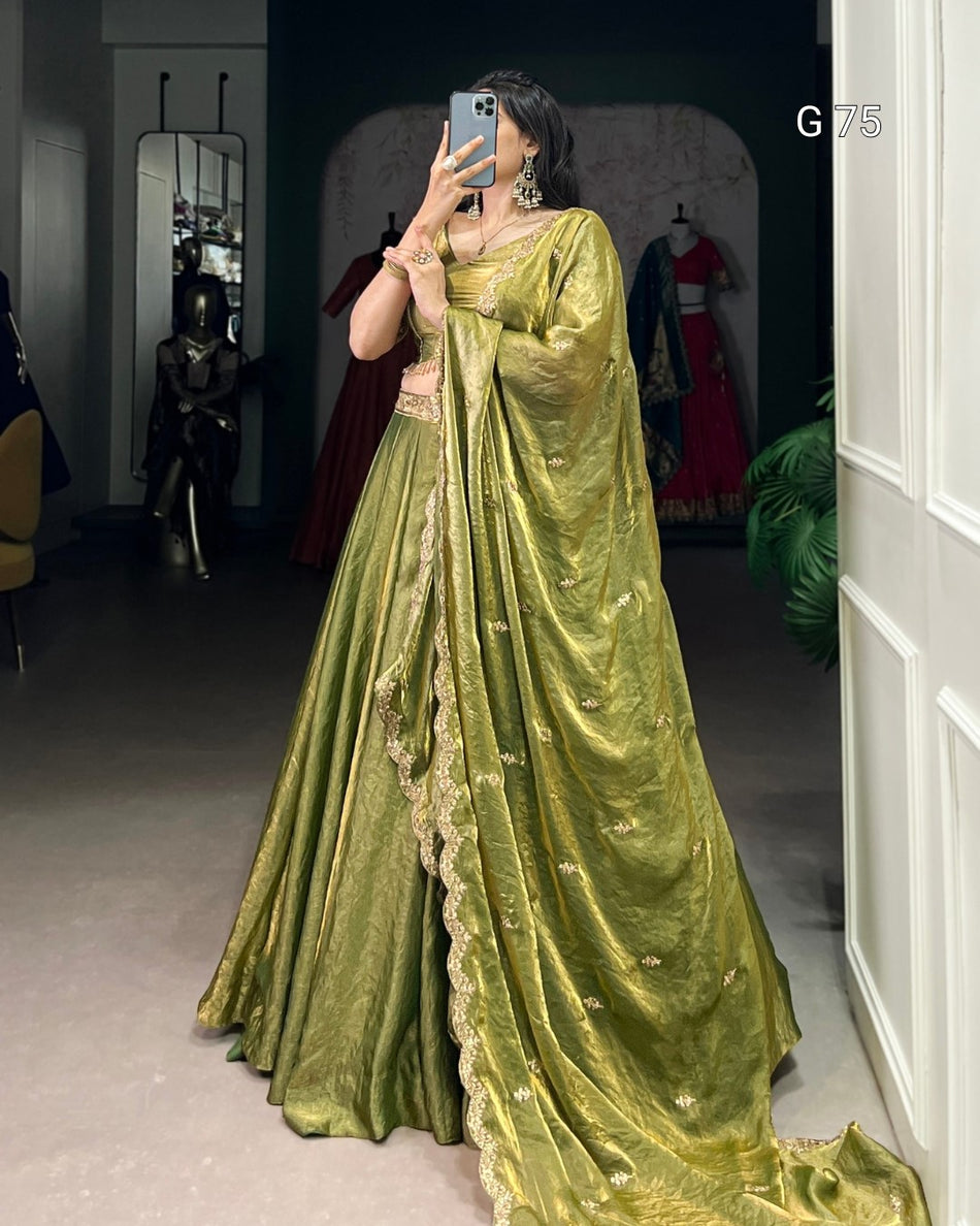 Person wearing a green saree with gold details, standing in a room.