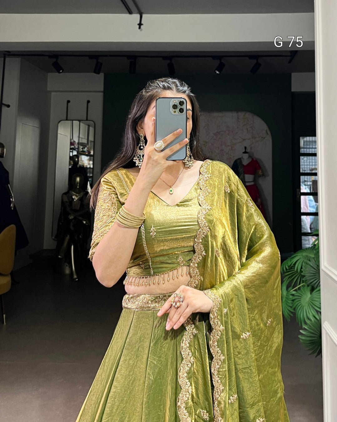 Person wearing a green traditional outfit with intricate designs in a room.