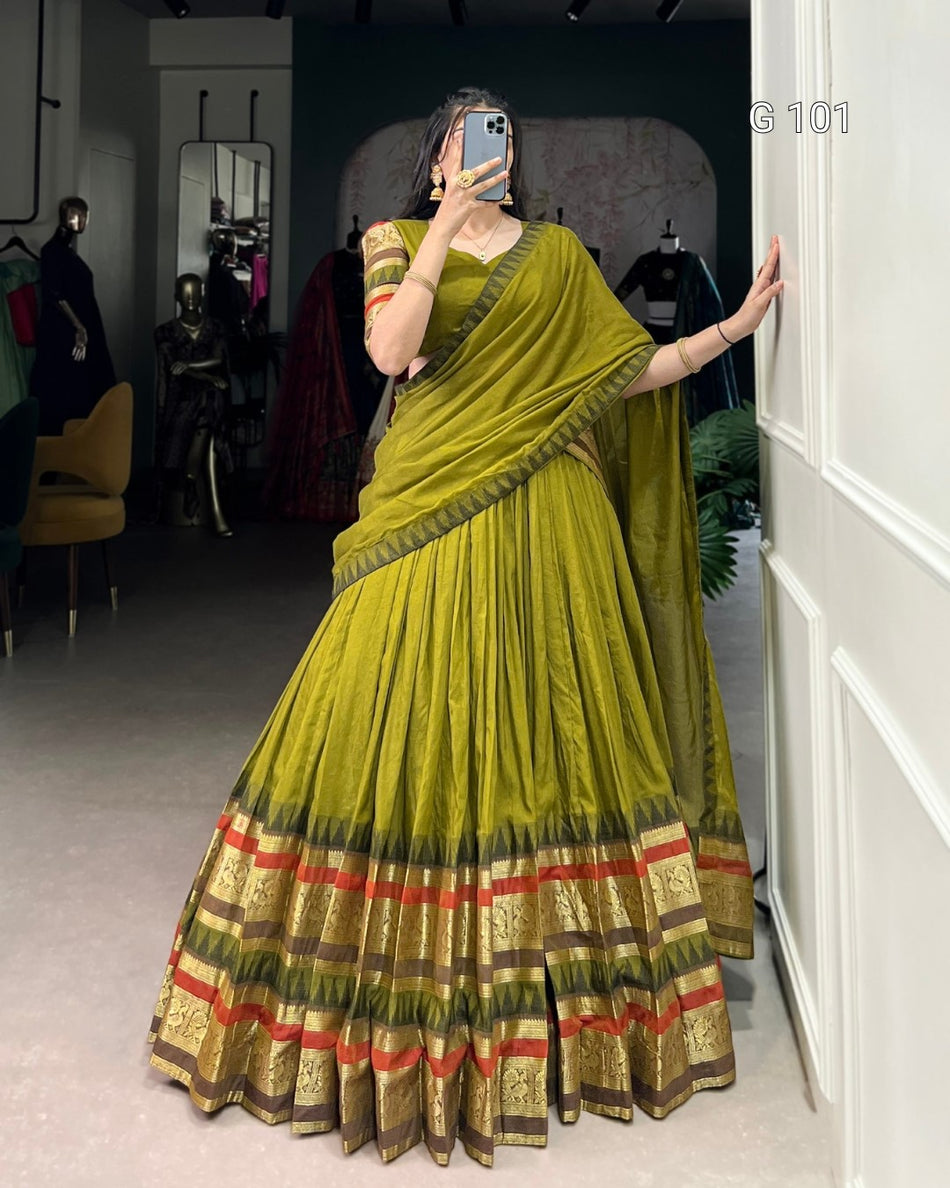 Woman wearing a green saree with red and gold patterns, taking a mirror selfie.