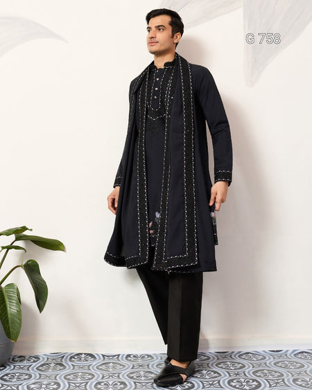 Man wearing a Navy Blue traditional outfit with a long jacket against a white wall.