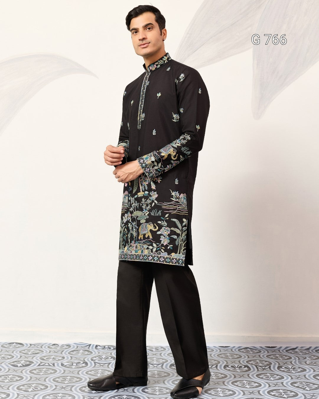 Man wearing a black kurta with intricate patterns on a white background