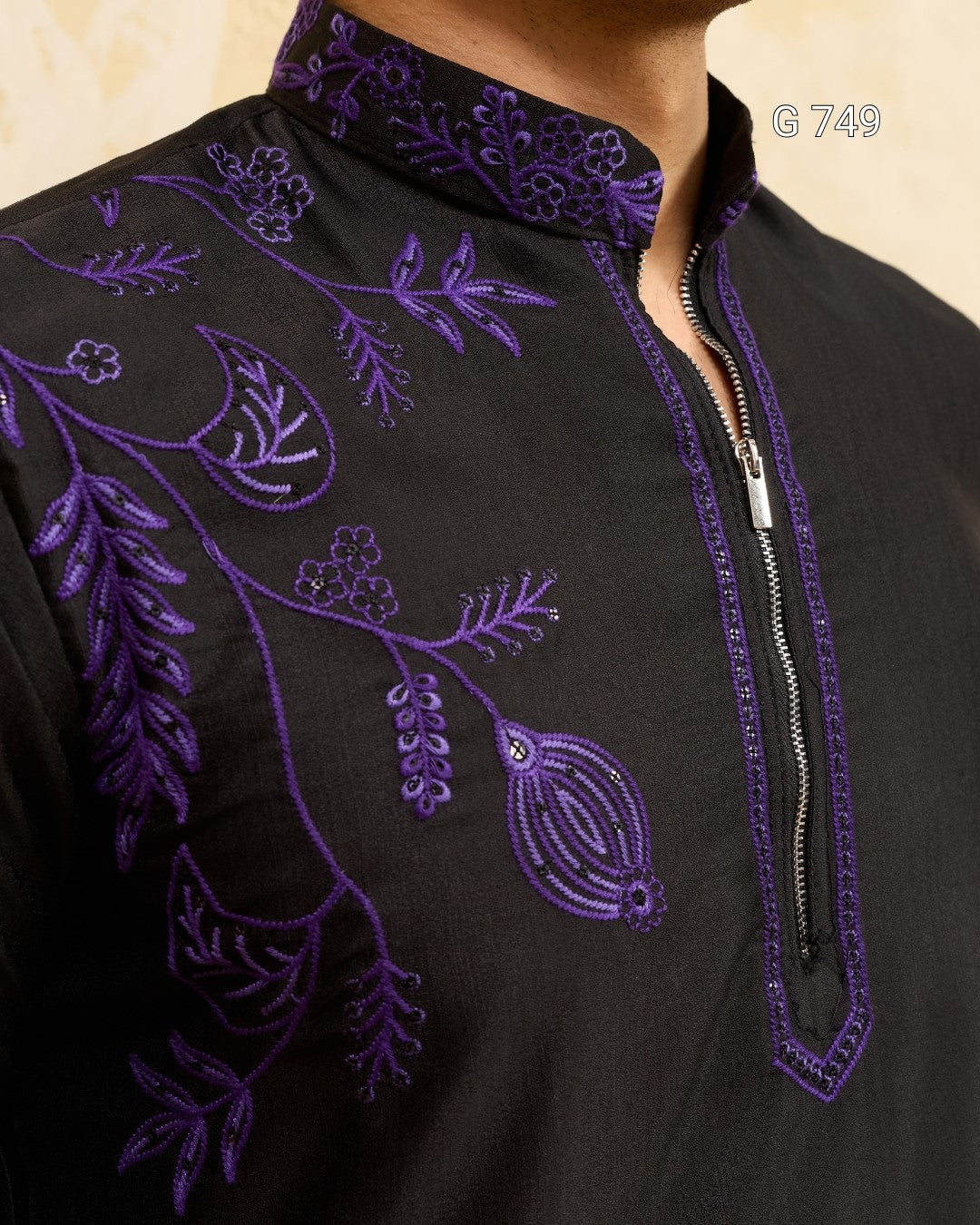Black garment with intricate purple embroidery on a beige background