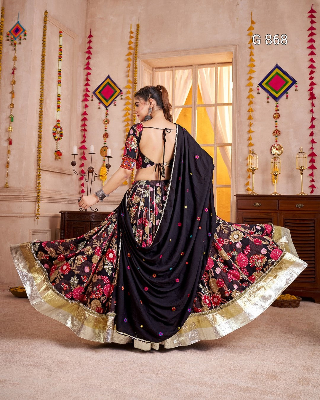 Woman in a traditional black and floral saree with decorative background