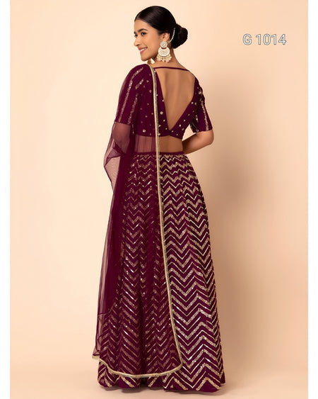 A woman modeling a deep purple/maroon traditional Indian outfit with gold chevron embroidery, shown from the back against a solid beige background.