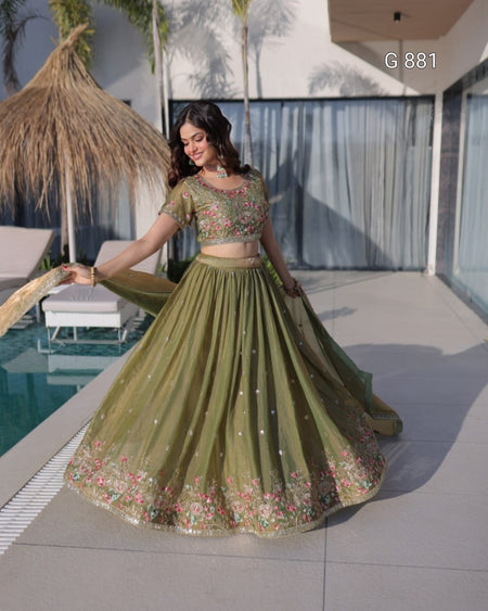 Woman in a green traditional outfit standing by a poolside.