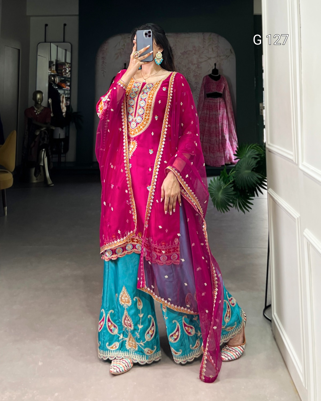 Person wearing a traditional outfit with a pink dupatta and blue palazzo pants in a room.