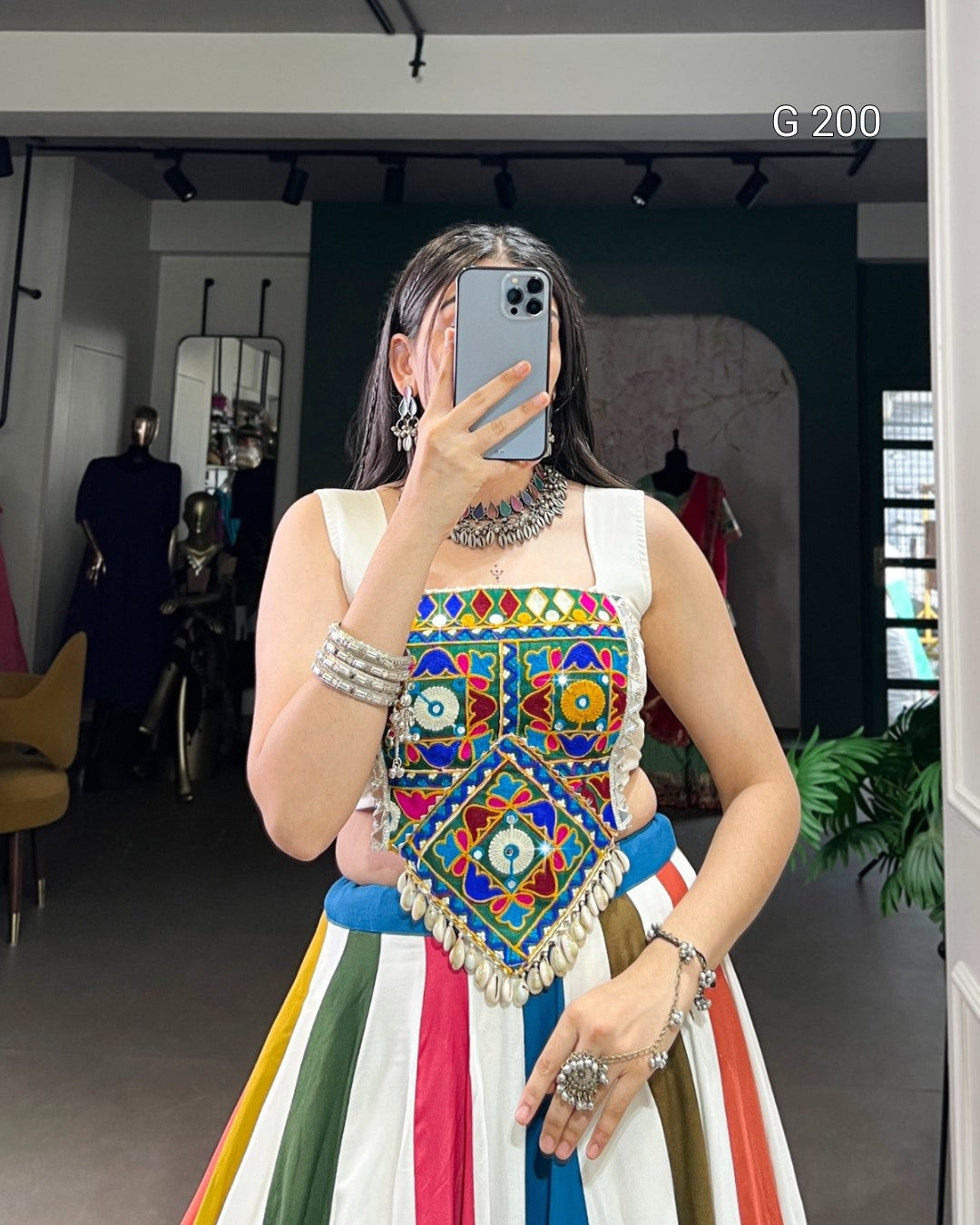 Person wearing a colorful traditional outfit with intricate patterns, taking a mirror selfie.
