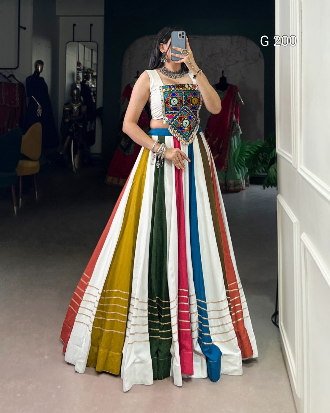 Woman wearing a colorful traditional outfit with a patterned top and striped skirt in a store setting.