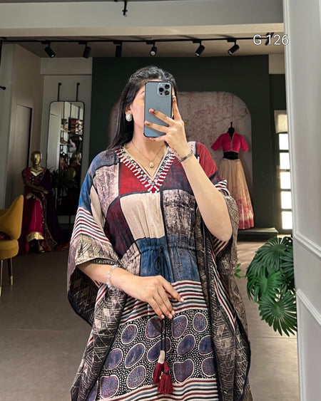 Woman taking a mirror selfie wearing a patterned dress in a room with decor elements.