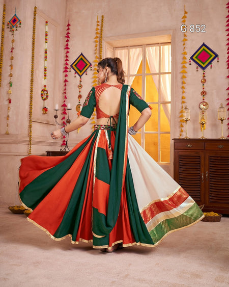 Woman in a colorful saree standing in a decorated room with hanging decorations.