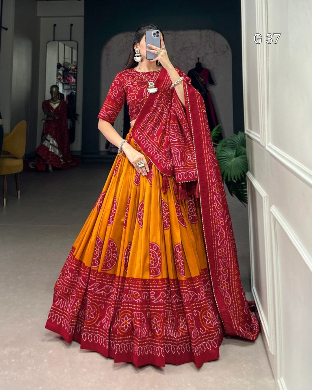 Person wearing a red and yellow traditional outfit with a patterned dupatta, standing in a room.