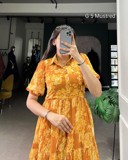 Person wearing a yellow floral dress taking a mirror selfie in an indoor setting.