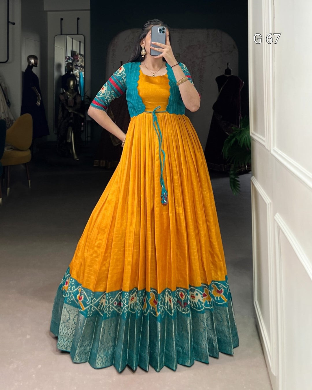 Person wearing a yellow and teal traditional outfit taking a mirror selfie.